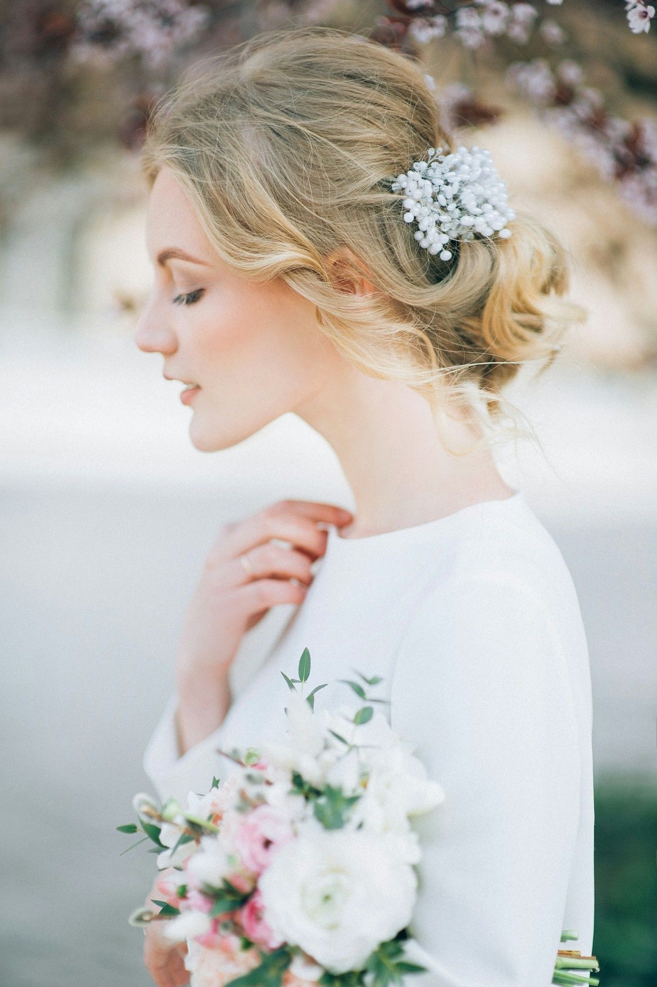 Bride with a pearl hair comb in a long-sleeve wedding dress, holding a bouquet